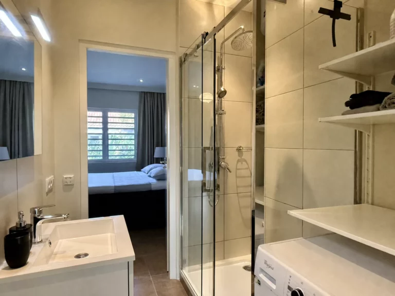 Badkamer van Casa Uthando met douche, wastafel en wasmachine